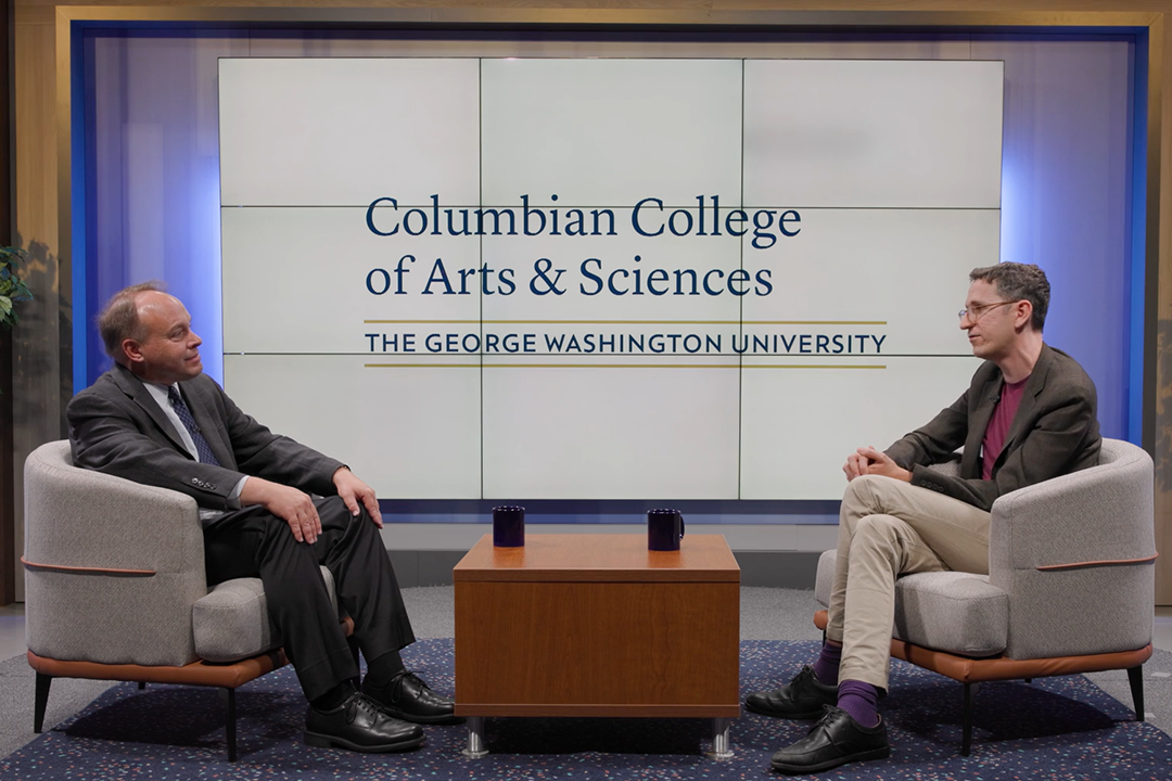 Dean Paul Wahlbeck seated on a stage across from Timothy Shenk, with a Columbian College logo behind them
