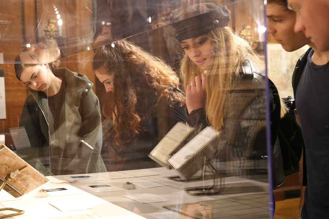 A group of students looking through a glass case at an old book at Mt. Vernon