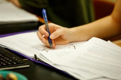 Close-up of a student writing in a binder with a pen.