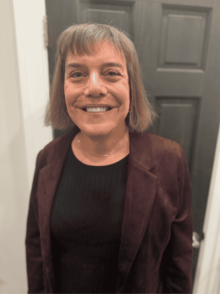 Headshot of Angela Zimmerman standing in front of a black door